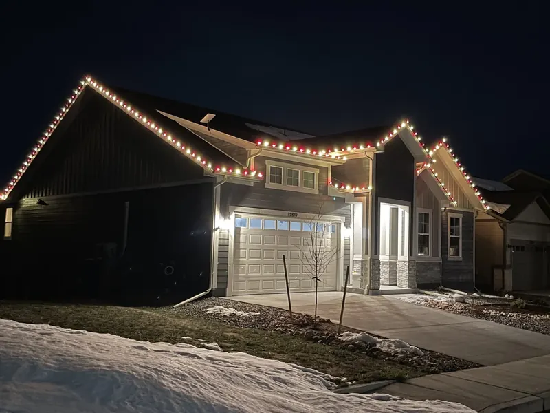 Gabled home with red and white lights above fresh snow