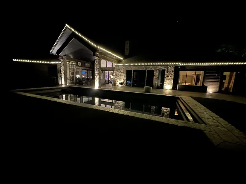 Modern home with warm white lights reflected in a pool